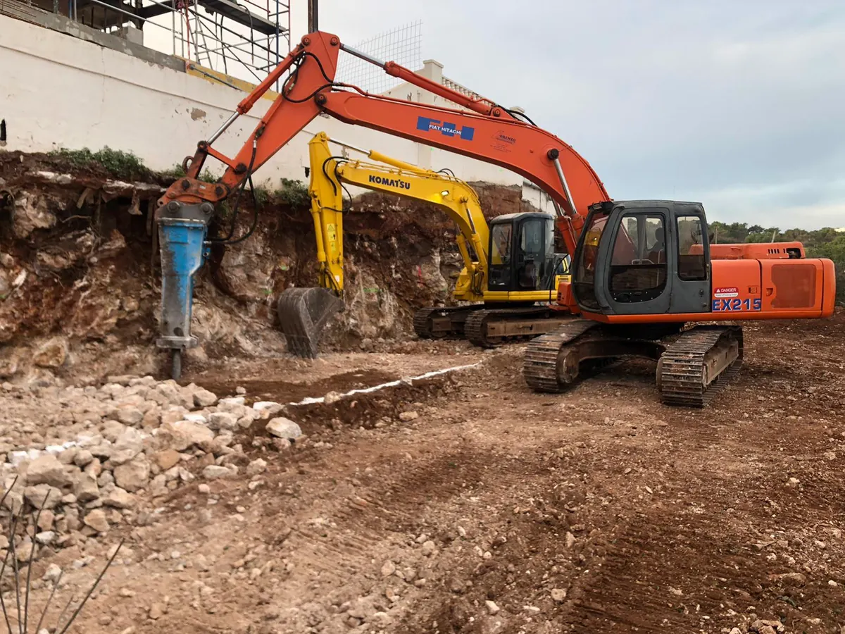 Dos excavadoras con martillo hidráulico trabajando en un desmonte de roca