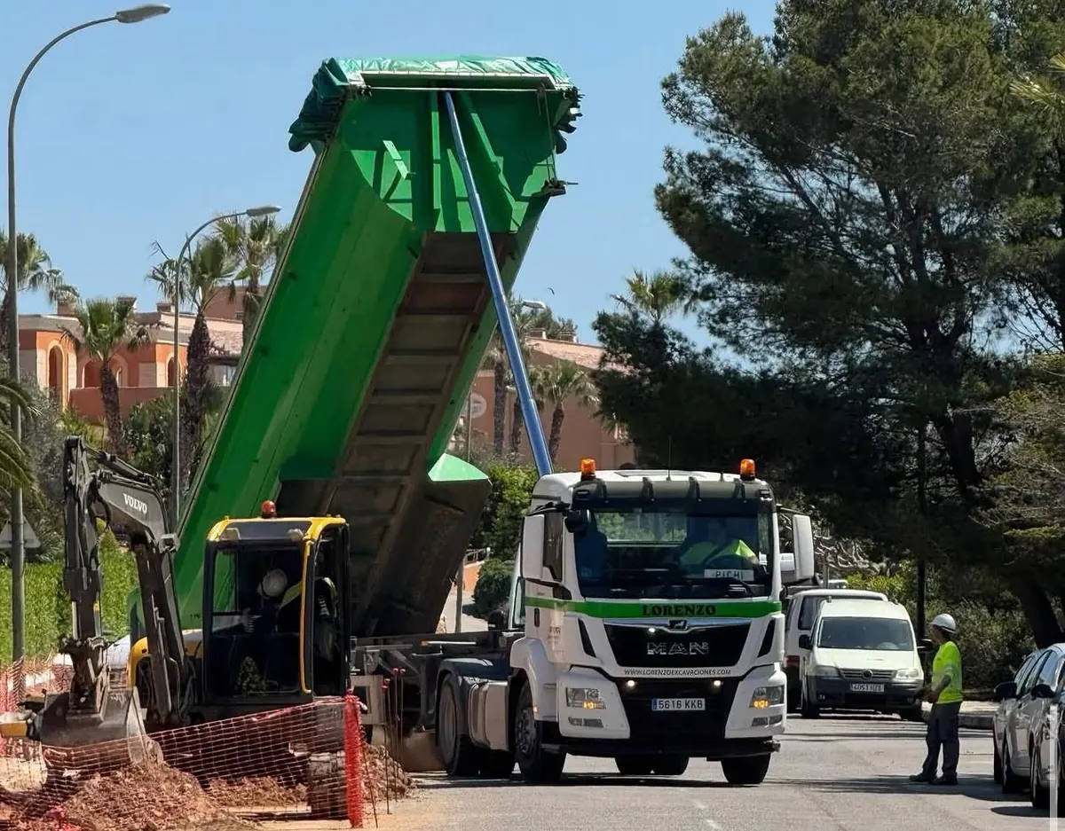 Camión bañera descargando material junto a una miniexcavadora