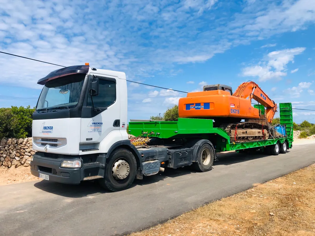 Low-loader carrying a tracked excavator along a road