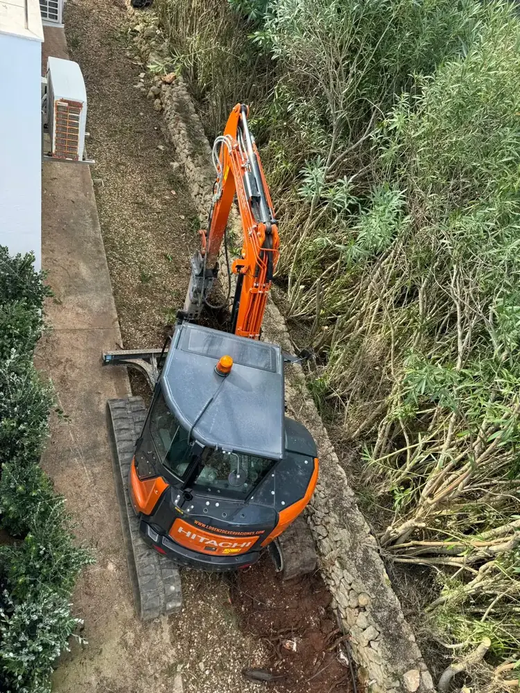Miniexcavadora trabajando entre la vegetación de una finca en Menorca