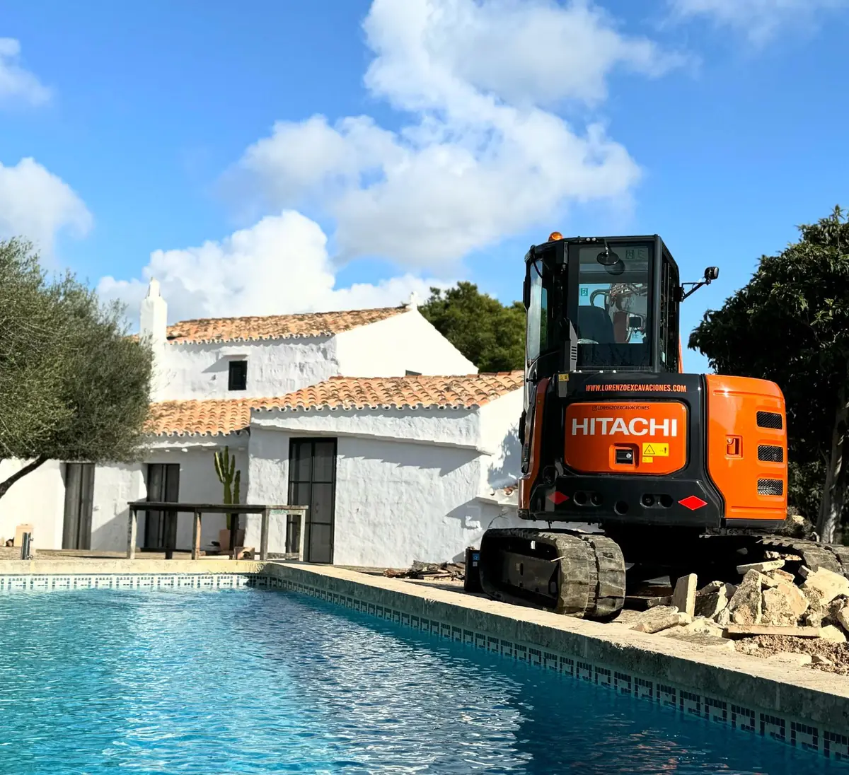 Miniexcavadora excavando al borde de una piscina en Menorca