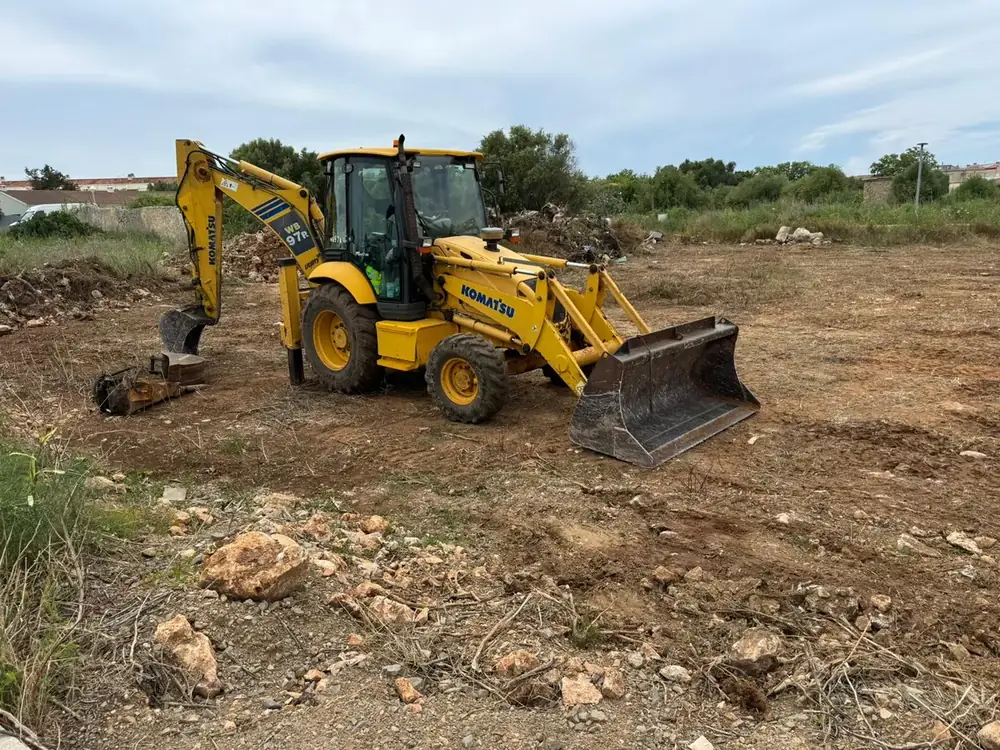 Komatsu WB97R backhoe loader with front bucket on a plot